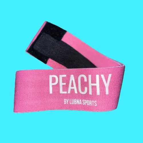 Roze booty weerstandsband met ’PEACHY’ erop gedrukt, gemaakt door Lubna Sports.